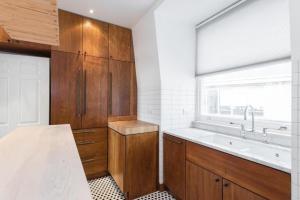 una cucina con armadi in legno, lavandino e finestra di The Leicester Square Apartment By Hok Living a Londra