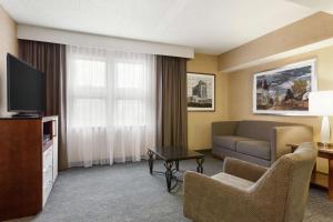 ein Wohnzimmer mit einem Sofa und einem TV in einem Hotelzimmer in der Unterkunft DoubleTree by Hilton Hotel Detroit - Novi in Novi