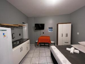 a room with a kitchen with a bed and a table at Pousada VSC in São Francisco do Sul