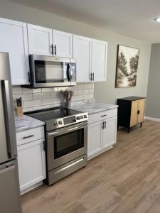 a kitchen with stainless steel appliances and white cabinets at Birdie Mae - 2 bedroom House in DT Hamilton in Hamilton