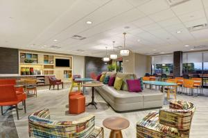 a lobby with a couch and tables and chairs at Home2 Suites By Hilton Madison Huntsville Airport in Madison