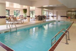 uma grande piscina num hotel com cadeiras e mesas em Hampton Inn & Suites Kokomo em Kokomo