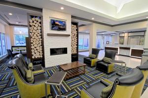 a lobby with a waiting room with chairs and a fireplace at Hilton Garden Inn Westbury in Westbury