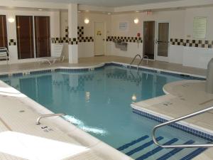 a large swimming pool with blue water in a building at Hilton Garden Inn Westbury in Westbury +26 photos