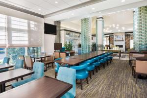 un comedor con mesas y sillas azules en Hilton Garden Inn Westbury, en Westbury