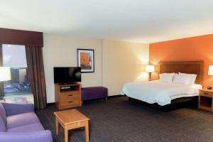 a hotel room with a bed and a flat screen tv at Hampton Inn Muskegon in Muskegon Heights
