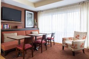 Habitación de hotel con mesas, sillas y TV de pantalla plana. en Hampton Inn Minneapolis-Burnsville, en Burnsville