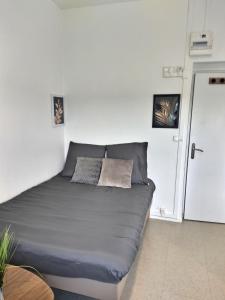 a bed in a room with a white wall at Superbe Studio 2 *Face Gare * Belle Vue Sur Balcon in Évreux