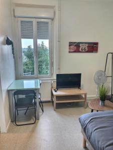 ein Wohnzimmer mit einem Schreibtisch und einem Tisch in der Unterkunft Superbe Studio 2 *Face Gare * Belle Vue Sur Balcon in Évreux