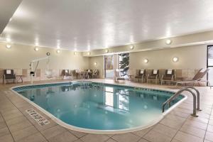 Hampton Inn Minneapolis St. Paul-Woodbury في وودبري: مسبح في غرفة الفندق مع الكراسي والطاولات