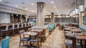 a restaurant with wooden tables and chairs and a bar at DoubleTree by Hilton Hotel West Palm Beach Airport in West Palm Beach