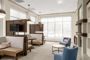 モリスビルにあるHilton Garden Inn Raleigh Durham Airportの椅子、テーブル、テレビが備わる待合室