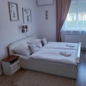 Cama blanca en habitación con ventana en Edina Vintage Vendégház en Mosonmagyaróvár