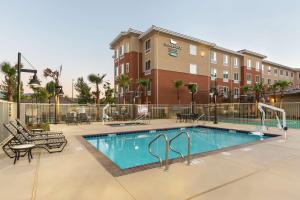 a swimming pool with chairs and a building at Homewood Suites by Hilton San Bernardino in San Bernardino