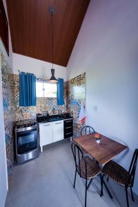 eine Küche mit einem Tisch, Stühlen, einer Spüle und einem Herd in der Unterkunft Flats 2 Locação Penedo RJ in Penedo