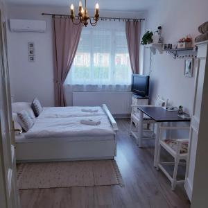 a bedroom with a bed and a desk and a television at Edina Vintage Vendégház in Mosonmagyaróvár