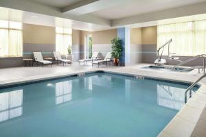 una piscina in una camera d'albergo con sedie e tavoli di Hilton Garden Inn Toledo / Perrysburg a Perrysburg