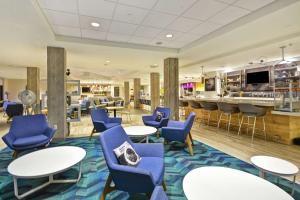 a lobby with blue chairs and tables and a bar at Home2 Suites by Hilton Perrysburg Levis Commons Toledo in Perrysburg