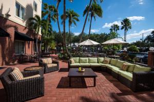 a patio with couches and tables and palm trees at Hilton Garden Inn Tampa Ybor Historic District in Tampa