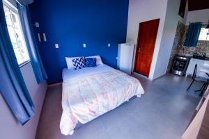 um quarto com uma cama e uma parede azul em Flats 2 Locação Penedo RJ em Penedo