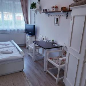 a room with a table and chairs and a television at Edina Vintage Vendégház in Mosonmagyaróvár