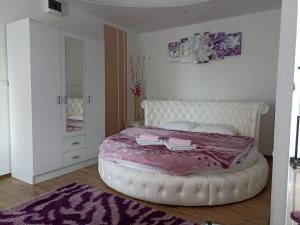 a bedroom with a white bed with a pink blanket at Apartmani Slađo in Trebinje
