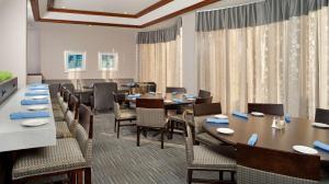 ein Esszimmer mit Tischen, Stühlen und Vorhängen in der Unterkunft DoubleTree by Hilton Hotel Chicago Wood Dale - Elk Grove in Wood Dale