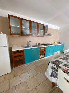 una cucina con armadi blu e frigorifero bianco di Magellano Apartments a Pontecagnano