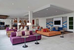 - un hall avec des tables et des canapés violets et orange dans l'établissement Hilton Garden Inn Madison Huntsville Airport, à Madison
