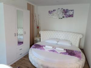 a white bedroom with a white bed and a mirror at Apartmani Slađo in Trebinje