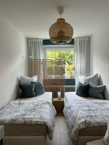 a bedroom with two beds and a window and a chandelier at Wohnen am Schloss in Wolfsburg