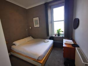 ein kleines Schlafzimmer mit einem Bett und einem Fenster in der Unterkunft The Haymarket Flat in Edinburgh