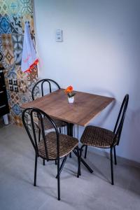 uma mesa de madeira com duas cadeiras e uma mesa com flores em Flats 2 Locação Penedo RJ em Penedo