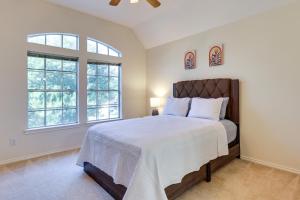 a bedroom with a large bed and two windows at Spacious Sugar Land Retreat with Fireplace and Yard in Sugar Land