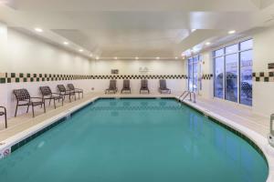 a swimming pool with chairs and a table in a building at Hilton Garden Inn Richmond South/Southpark in Colonial Heights
