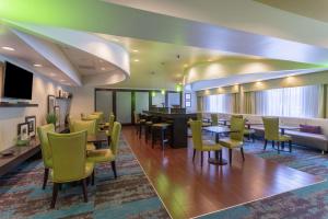 里士滿的住宿－里士滿南希爾頓恆庭酒店，一间设有黄色桌椅的餐厅和一间酒吧