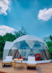 Tienda de campaña con sillas y mesas en una terraza en Phalesia Glamping Otel, en Sapanca