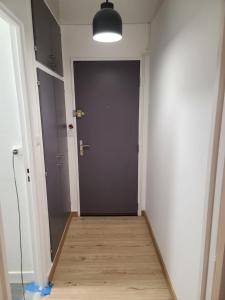 pasillo con puerta negra y suelo de madera en Magnifique Studio 26m2, en Belfort