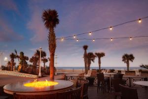 un patio con mesas y sillas y vistas a la playa en Hilton Virginia Beach Oceanfront, en Virginia Beach