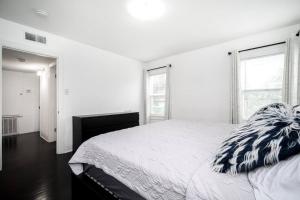 a white bedroom with a bed and two windows at Trendy Apartment in Downtown - Near Montrose in Houston