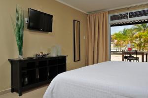 a bedroom with a bed and a flat screen tv at Eden Beach Resort - Bonaire in Kralendijk