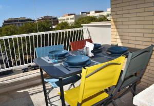 a table with blue plates and yellow chairs on a balcony at Mau Beach House in Lido di Ostia