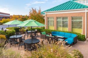 un patio con tavoli, sedie e ombrelloni verdi di Hilton Garden Inn Washington DC/Greenbelt a Greenbelt
