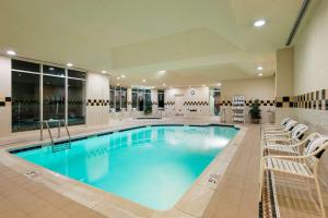 a large swimming pool with white chairs in a hotel at Hilton Garden Inn Washington DC/Greenbelt in Greenbelt