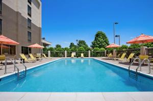 a swimming pool at a hotel with chairs and umbrellas at Hampton Inn Lexington Park in Lexington Park