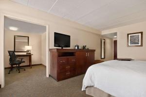ein Hotelzimmer mit einem Bett und einem Schreibtisch mit einem TV in der Unterkunft Hampton Inn Lexington Park in Lexington Park