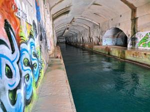 a tunnel with graffiti on the side of a river at Stone Rose Glamping & Apartments in Tivat