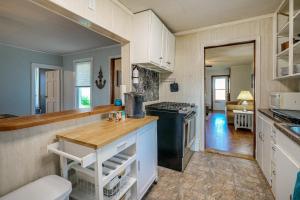 a kitchen with white cabinets and a black stove at Downtown Russells Point Cottage Near Indian Lake! in Russells Point