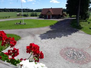 a gravel driveway with red flowers in front of a house at Viki talu in Jõõpre