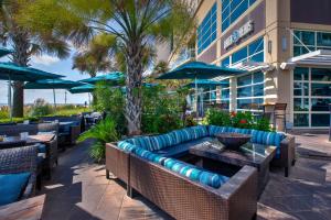 eine Terrasse mit einem Sofa, Tischen und Sonnenschirmen in der Unterkunft Hilton Garden Inn Virginia Beach Oceanfront in Virginia Beach